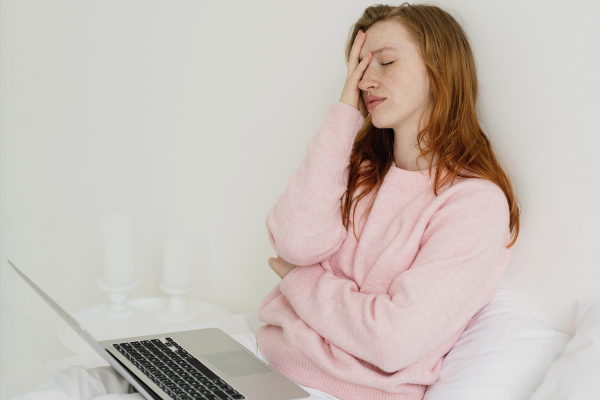 A woman face pams while sitting with her computer looking frustrated.
